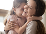 Smiling mother cuddling her young daughter